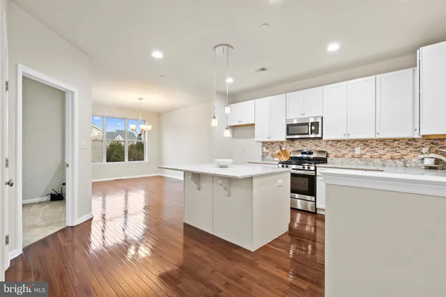 a kitchen with kitchen island granite countertop a sink cabinets and wooden floor
