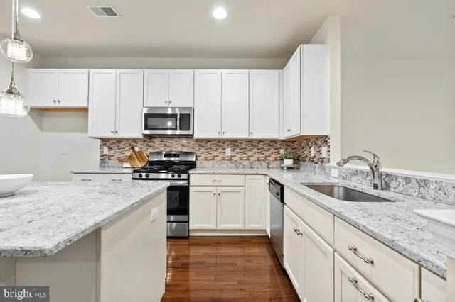 a kitchen with granite countertop a sink stove and cabinets