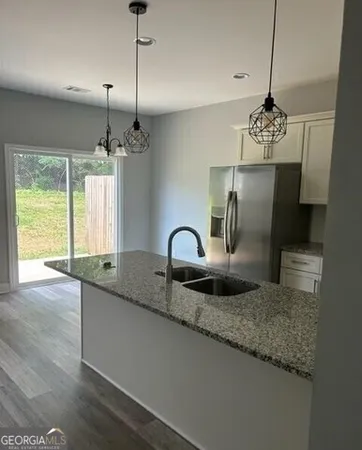 a kitchen with kitchen island granite countertop a stove a refrigerator wooden floor and a large window