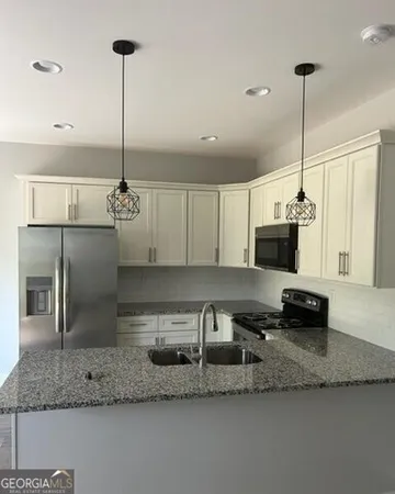 a kitchen with stainless steel appliances granite countertop a sink a counter space and cabinets