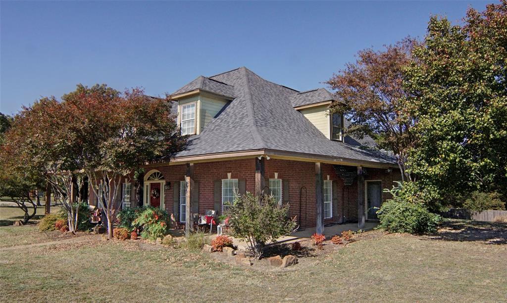 216 Sam Bass Road Willow Park, TX 76087 - Photo 4 of 34 View of front facade featuring brick siding, a front yard, covered porch, and a shingled roof