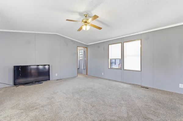 an empty room with windows and fan