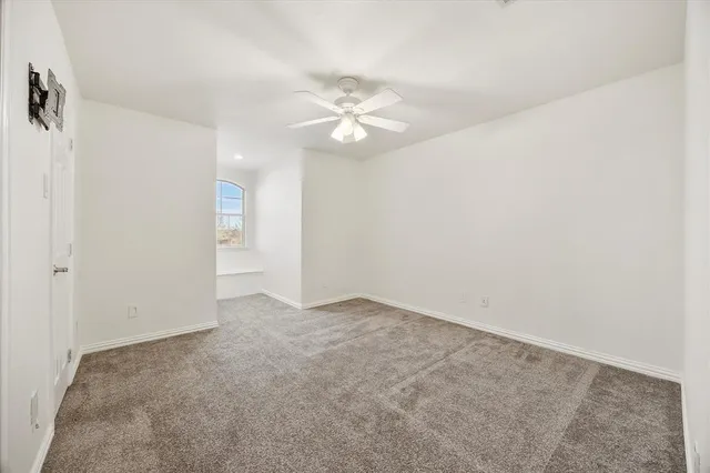 an empty room with a ceiling fan and a window