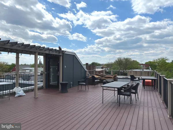 a view of roof deck with table and chairs a barbeque with wooden floor and fence
