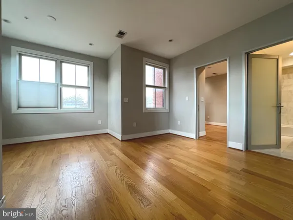 an empty room with wooden floor and windows