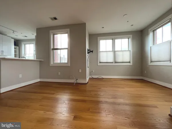 an empty room with wooden floor and windows