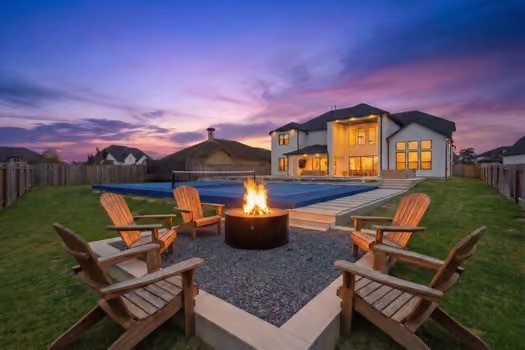 Dramatic evening backyard view combining luxury, leisure, and activity with pool, fire pit, and pickleball court