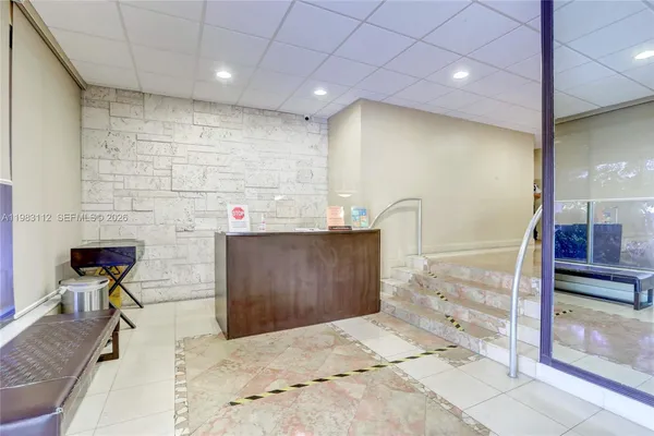 a hall with stainless steel appliances kitchen island granite countertop a sink and cabinets