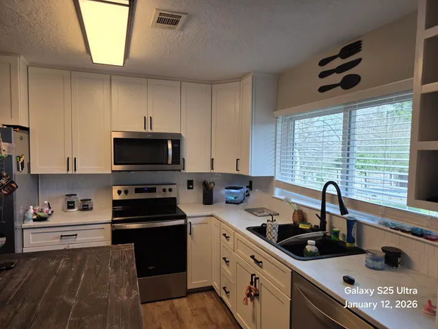 a kitchen with stainless steel appliances a sink a stove a microwave a sink and cabinets