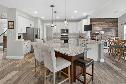a large kitchen with granite countertop lots of counter space dining table and stainless steel appliances