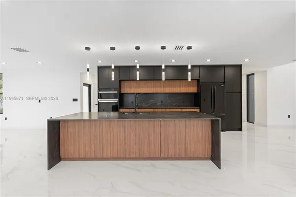 a large kitchen with stainless steel appliances a large counter top a sink and a refrigerator