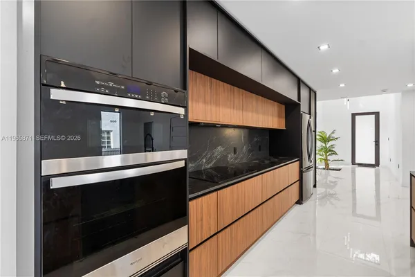 a living room with stainless steel appliances kitchen island granite countertop a refrigerator and a stove top oven