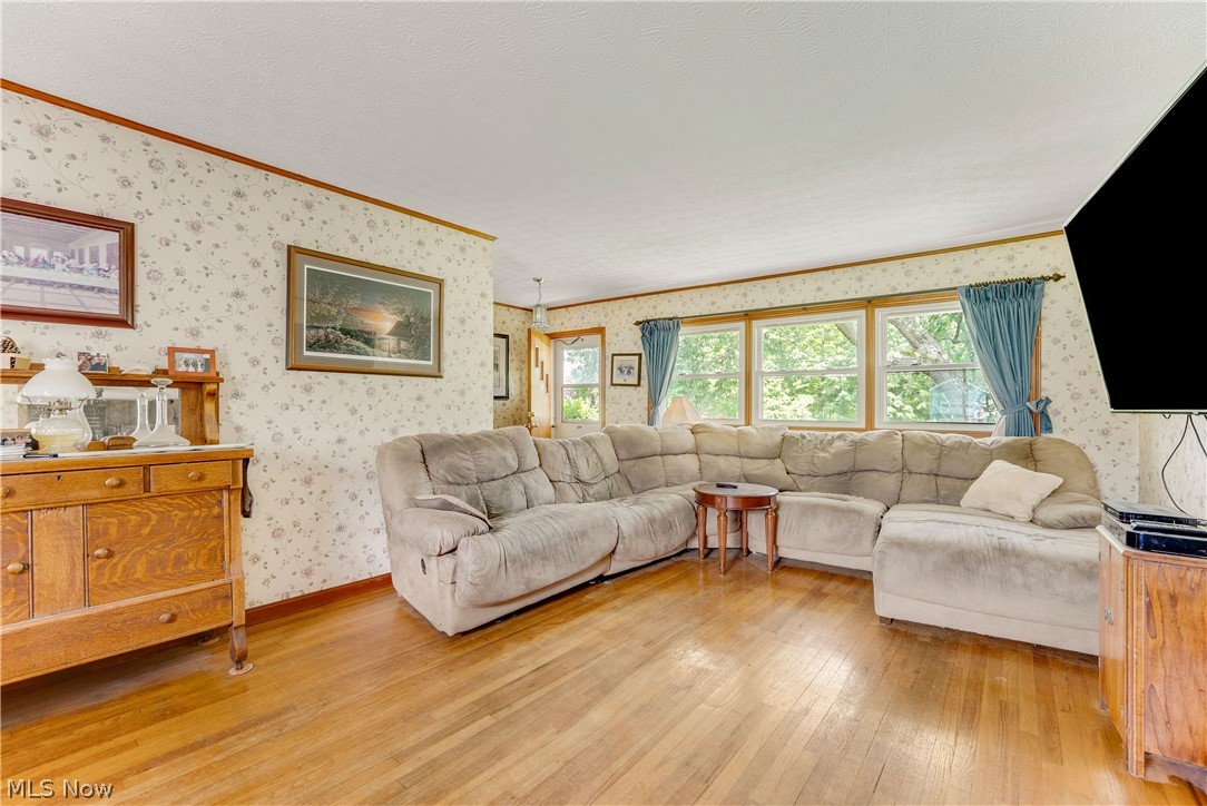 16107 Moseley Road Madison, OH 44057 - Photo 11 of 40 Bright living area featuring wood flooring, patterned wallpaper, and a multi-pane window configuration