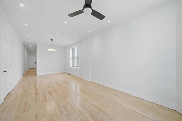 a view of empty room with wooden floor and fan