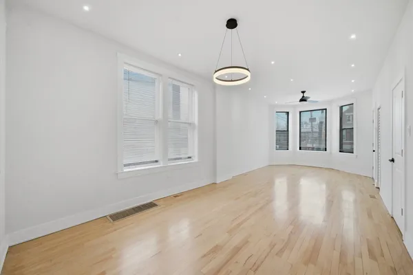 a view of an empty room with a window and wooden floor