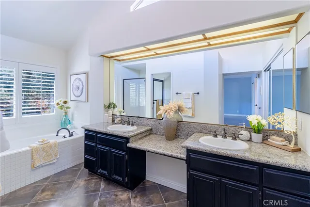 a bath room with a granite countertop tub sink and mirror