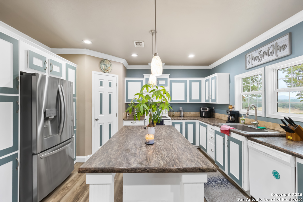 201 Private Road 1524 Bandera, TX 78003 - Photo 11 of 36 a kitchen with stainless steel appliances granite countertop a refrigerator a stove a sink a refrigerator white cabinets and wooden floor