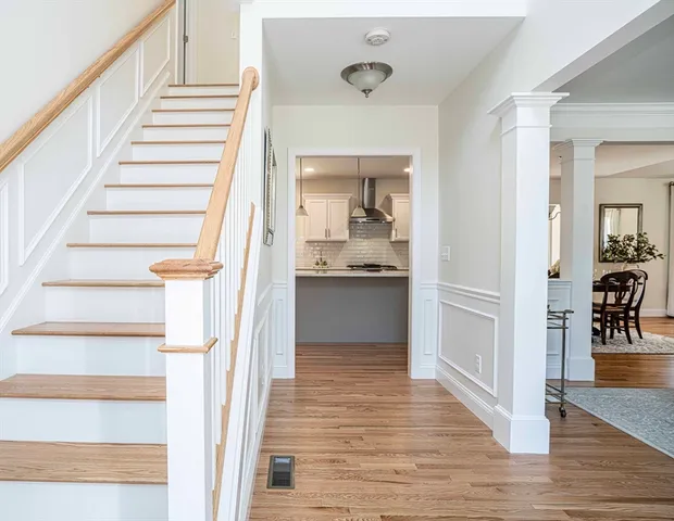 a view of an entryway with wooden floor and a kitchen view