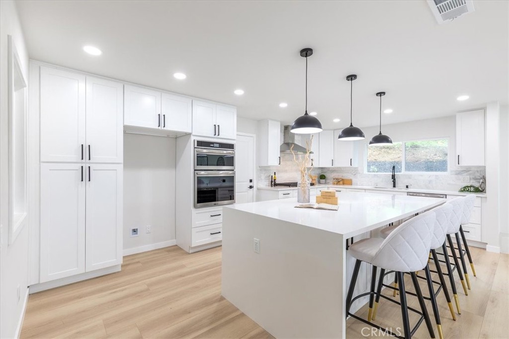26005 Adamor Road Calabasas, CA 91302 - Photo 5 of 34 a kitchen with stainless steel appliances kitchen island granite countertop a refrigerator a sink dishwasher a stove and a oven with wooden floor