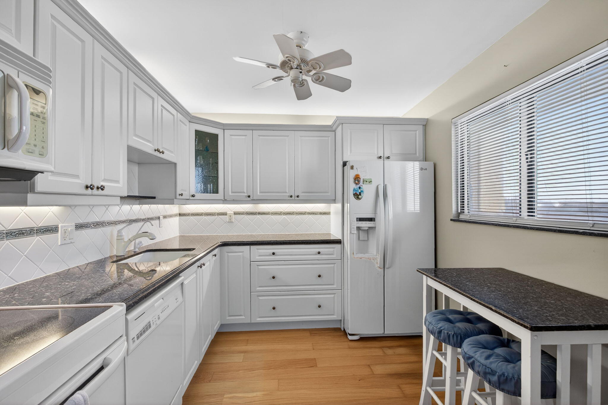 200 Ocean Trail Way, Unit 405 Jupiter, FL 33477 - Photo 13 of 46 a kitchen with stainless steel appliances granite countertop a refrigerator a sink dishwasher a stove and white countertops with wooden floor