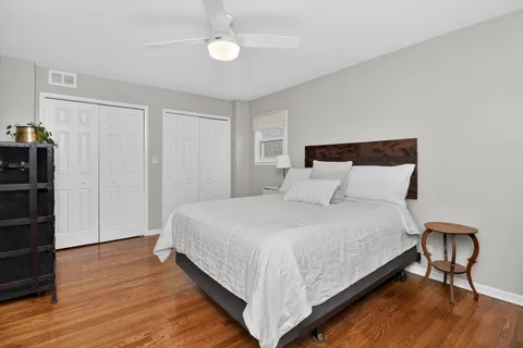a large bed in a bedroom next to a window with wooden floor
