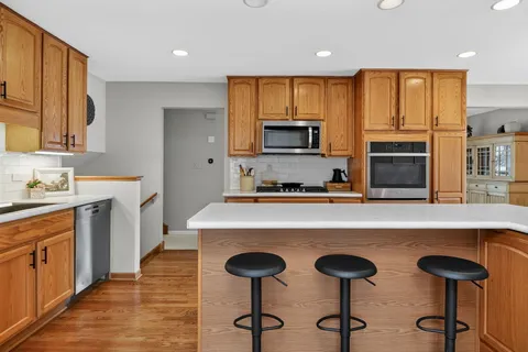 a kitchen with stainless steel appliances a stove a sink a microwave a refrigerator cabinets and dining table