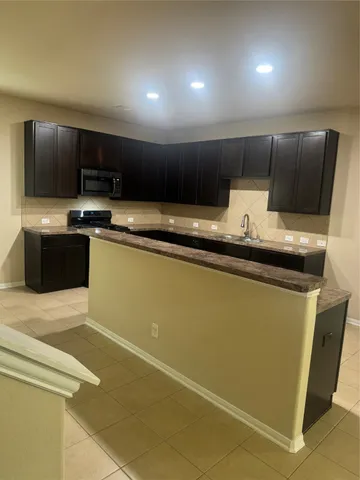 a kitchen with stainless steel appliances granite countertop a sink a stove a microwave and a refrigerator