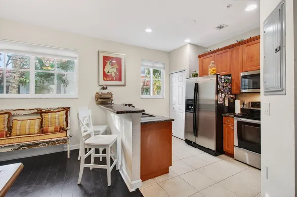 a kitchen with stainless steel appliances a refrigerator a stove a sink a dining table and chairs with wooden floor