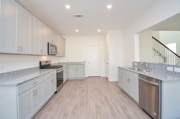 a kitchen with granite countertop a sink a counter top space stainless steel appliances and cabinets