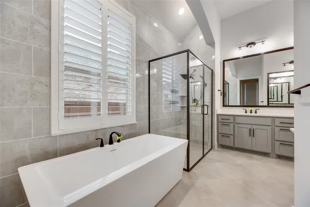 a bathroom with a tub a sink a mirror and a shower