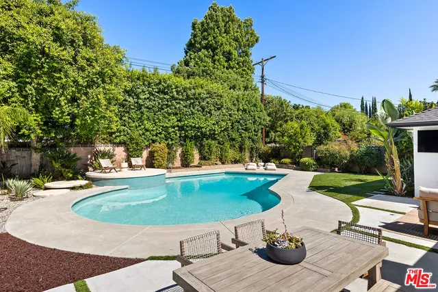 a view of a patio with table and chairs potted plants with wooden floor and fence