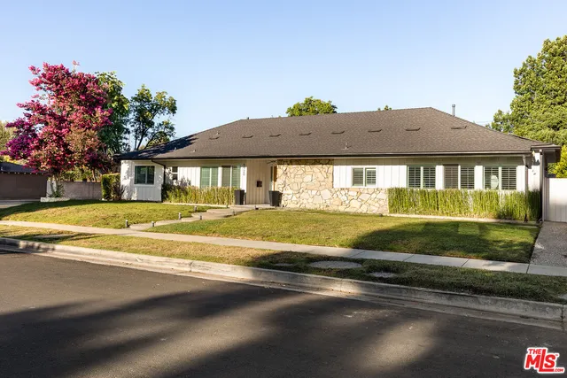 front view of house with a yard and palm trees