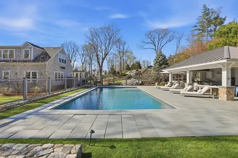 a view of swimming pool with outdoor seating and house in the background