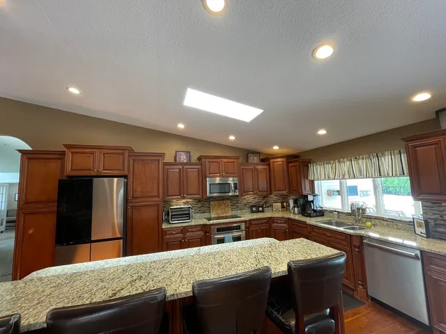a room with kitchen island stainless steel appliances a sink and wooden floor