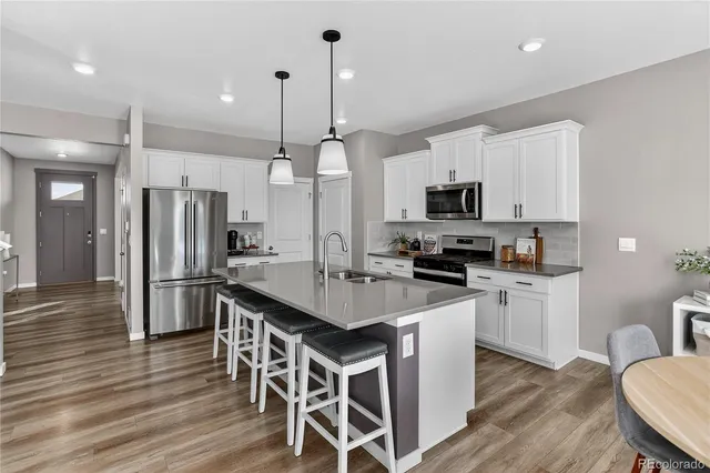 a kitchen with stainless steel appliances granite countertop a stove a refrigerator a kitchen island a sink and a refrigerator