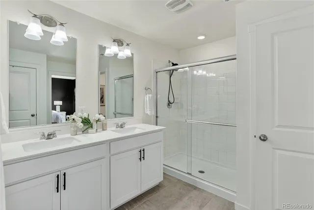 a bathroom with a double vanity sink mirror and shower