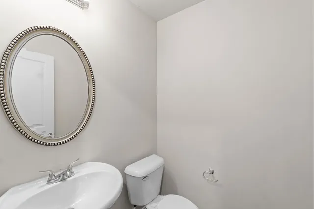 a bathroom with a toilet mirror a sink and a mirror