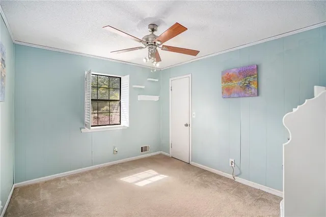 an empty room with windows and fan