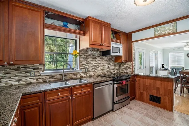 a kitchen with stainless steel appliances granite countertop a sink stove and cabinets