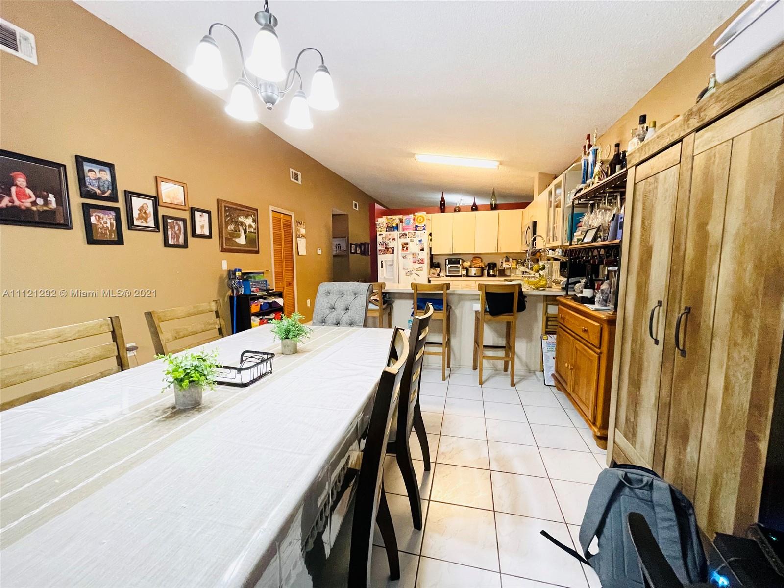 1245 Southwest 143rd Place Miami, FL 33184 - Photo 10 of 23 a kitchen with stainless steel appliances granite countertop a refrigerator a sink dishwasher a stove a dining table and chairs with wooden floor