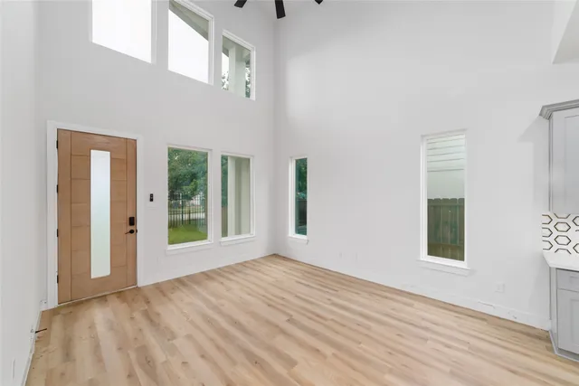 a view of an empty room with wooden floor and a window