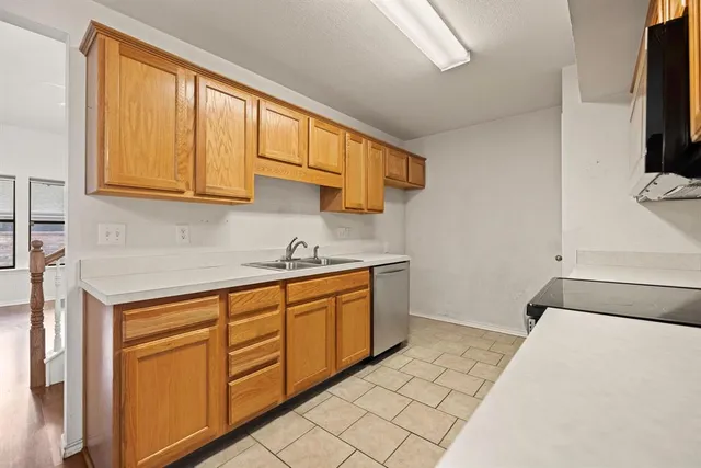 a kitchen with granite countertop a sink a stove top oven and cabinetry