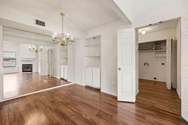 a view of an empty room with wooden floor and a ceiling fan