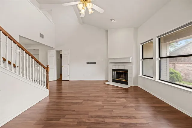 an empty room with wooden floor fireplace and windows