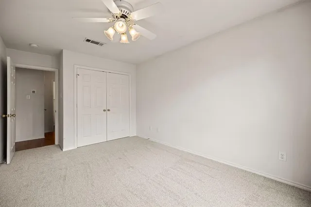 an empty room with windows and chandelier fan