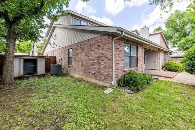 a backyard of a house with plants and large tree