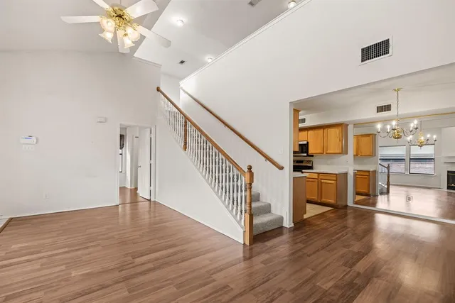 an empty room with wooden floor fireplace cabinet and windows