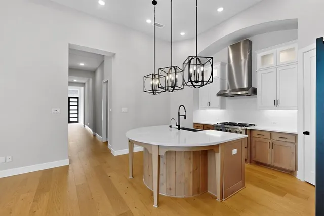 a kitchen with stainless steel appliances granite countertop a sink a stove and a wooden floors