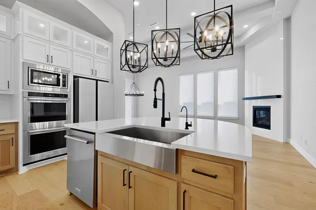 a kitchen with stainless steel appliances granite countertop a sink and dishwasher a refrigerator a oven with wooden floor