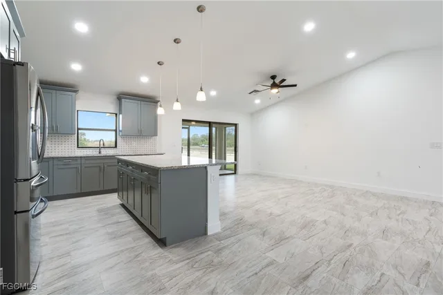 a large white kitchen with a large counter top a sink stainless steel appliances and cabinets